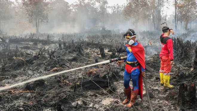 Seorang pelajar bernama Rudiansyah (kiri) memakai kostum Superman saat berupaya membantu memadamkan api diPetuk Katimpun, Palangkaraya, Kalimantan Tengah, pada 17 Agustus. 