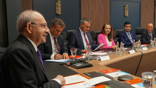Kılıçdaroğlu'nun baş koltukta oturduğu bir masa, yanında diğer parti yöneticileri var. Bir kadın renkli bir takım giymiş.