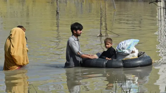 A family wades through waist-deep water in the Charsadda district of Pakistan's north western Khyber Pakhtunkhwa province
