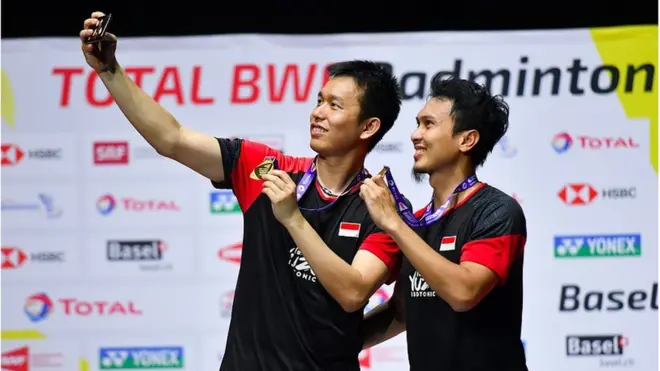 Ganda putra Indonesia Hendra Setiawan (kiri) dan Mohammad Ahsan berswafoto dengan menunjukan medali emas saat prosesi penyerahan medali pada Kejuaraan Dunia Bulu Tangkis 2019 di St. Jakobshalle, Basel, Swiss, Minggu (25/8).