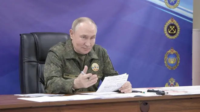 Vladimir Putin u vojnoj uniformi sedi za stolom