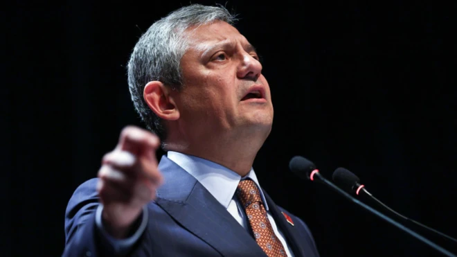 Özgür Özel sahnede elini kaldırmış şekilde konuşma yapıyor