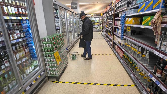 Shopper with lines on floor to mark social distancing in a supermarket
