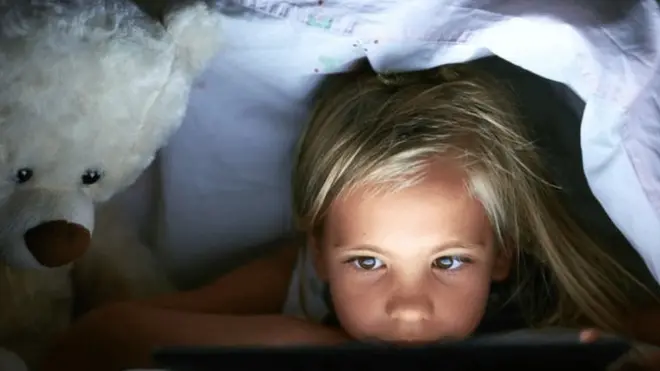 ребенок с гаджетом под одеялом