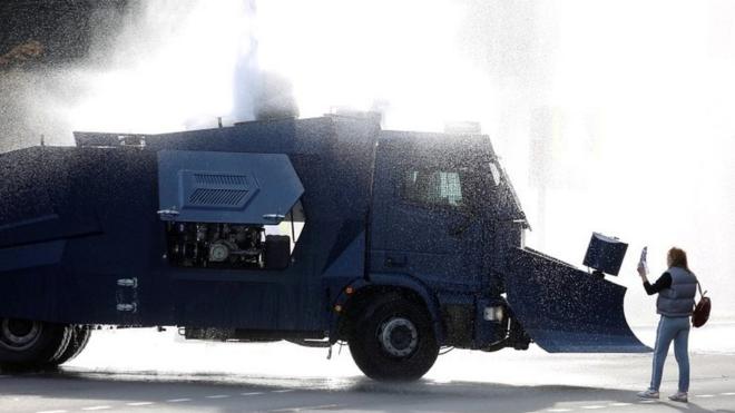 An opposition supporter stands next to a police water cannon truck during a rally to reject the presidential election results in Minsk on 4 October 2020