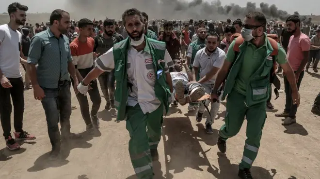 Palestinian medics carry a wounded protester near the border with Israel in the east of Jabaliya in the northern Gaza Strip, 14 May 2018