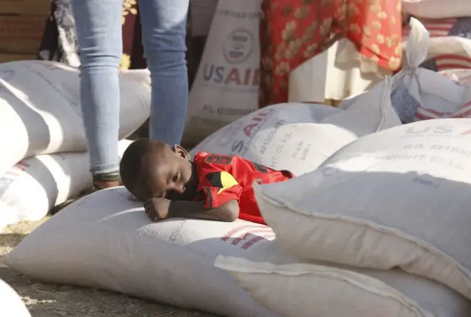 Un enfant couché sur un sac de céréales avec le logo de l'USAID