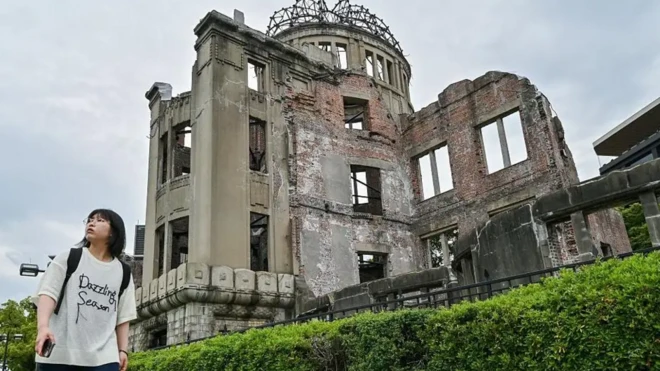 زنی در حال عبور از کنار یک ساختمان ویران