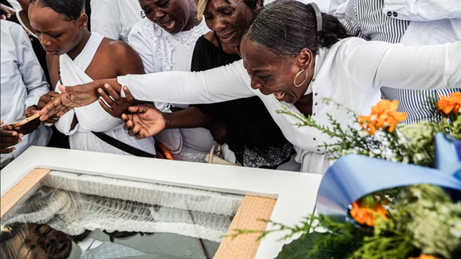 Mulheres choram sobre um caixão durante o enterro coletivo de oito pessoas mortas em um ataque com drones em Porto Príncipe, no Haiti, em 4 de outubro de 2025. O alvo dos drones era o suposto líder de uma gangue criminosa em um bairro de Porto Príncipe e acabou matando 11 civis no dia 20 de setembro daquele ano