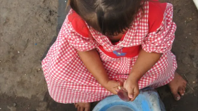 Una niña paraguaya lava unos cubiertos