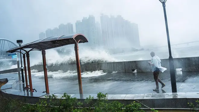 El viento y las olas azotan la costa mientras un hombre intenta pasar al lado
