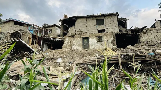 خانه‌های ویران از زلزله افغانستان در دورنمای تصویر دیده می‌شوند