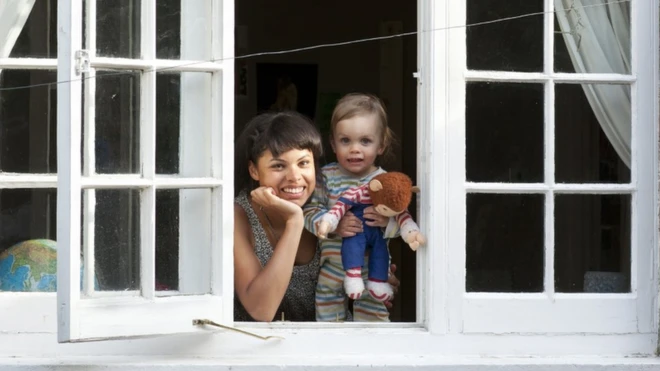 Woman and toddler looking out of an open window