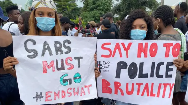 Two protesters carry placards for hands