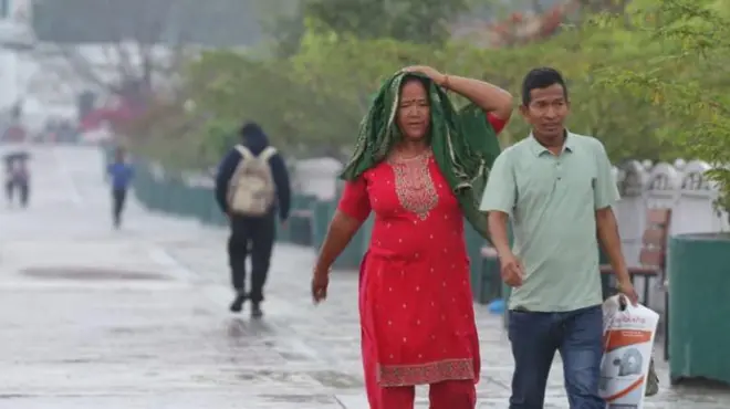 काठमाण्डूमा वर्षा भएपछि बाटोमा भिजेर हिँड्दै मानिसहरू