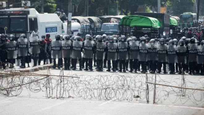 防暴警員手持盾牌，在仰光大學附近的街道上利用鐵線網布防