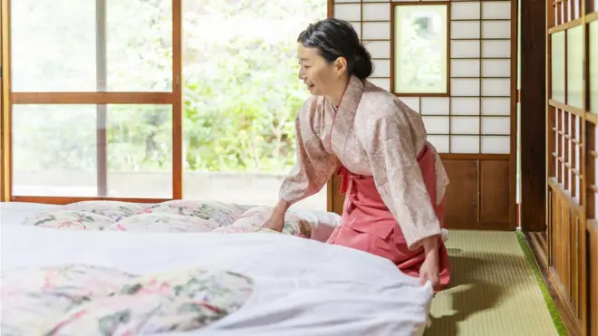 Una mujer oriental prepara un futón.