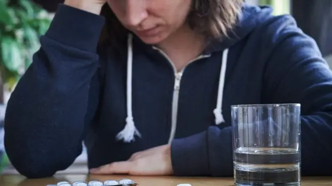 Une femme avec des pilules et un verre d'eau
