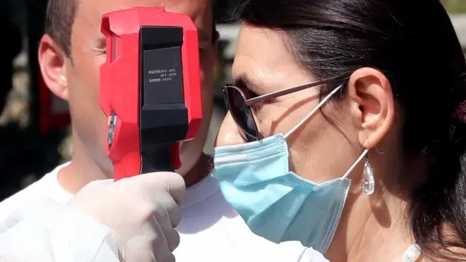 A woman's temperature is tested at a hospital in Sarajevo, Bosnia and Herzegovina, 31 August 2020