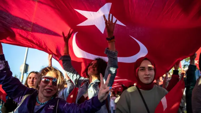 Mujeres debajo de una bandera gigante turca.