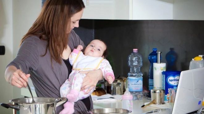 çalışırken çocuk bakıp yemek yapan bir kadın
