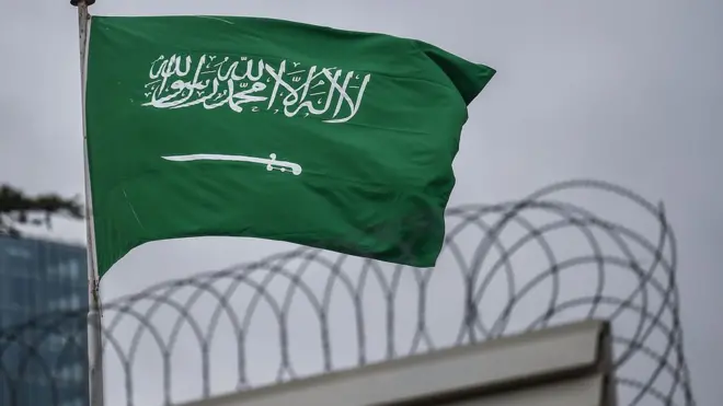 علم السعودية أعلى سور بجانب سلك شائك