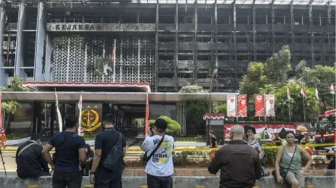 Warga menyaksikan petugas pemadam kebakaran melakukan proses pendinginan di gedung utama Kejaksaan Agung yang terbakar di Jakarta, Minggu (23/08).