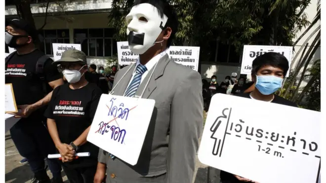 People affected by the Covid-19 situation gather with banners to protest how the government handles the Covid-19 coronavirus crisis outside the Government House, in Bangkok