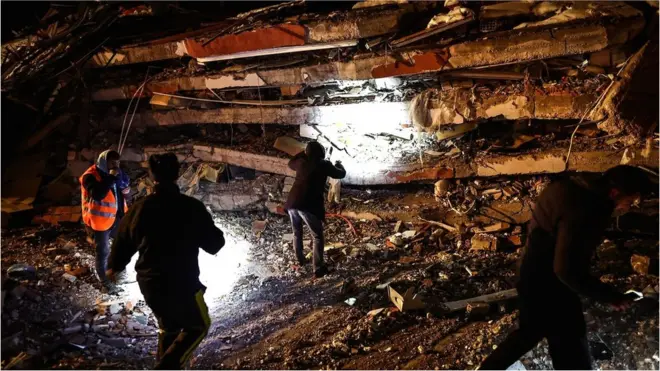 Emergency personnel search for victims at the site of a collapsed building in the aftermath of a powerful earthquake in the Elbistan district of Kahramanmaras, south-eastern Turkey, on 7 February 2023