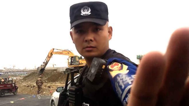 Policeman raises hand to stop the BBC camera from filming