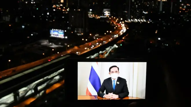 ภาพพล.อ. ประยุทธ์ จันทร์โอชา บนหน้าจอโทรศัพท์วางหน้ารถ ฉากหลังเป็นถนนในกรุงเทพฯ