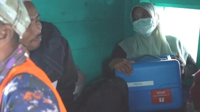 Arina Astuti, Koordinator Imunisasi Puskesmas Pulo Aceh, membawa kotak berisi vaksin Covid-19 dengan menumpang kapal.
