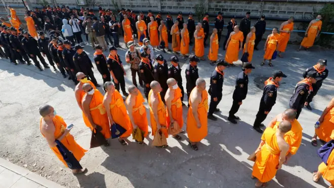 Polisi dan biksu berbaris berdampingan di Kuil Dhammakaya, tempat Phra Dhammajayo diduga bersembunyi.