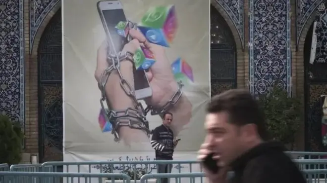 متظاهر أمام لافتة في إيران