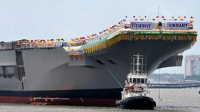 Tugboats guide the indigenously-built aircraft carrier INS Vikrant as it leaves the dock of the Cochin Shipyard after the launch ceremony in Kochi on August 12, 2013.