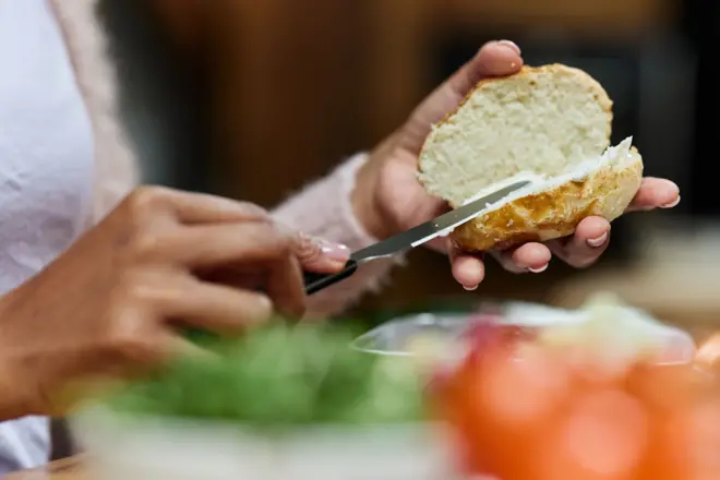 Woman spreading butter on her bun