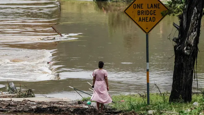 Жена стоји и гледа у реку