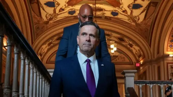 El director de la CIA, John Ratcliffe, con un hombre caminando detrás de él