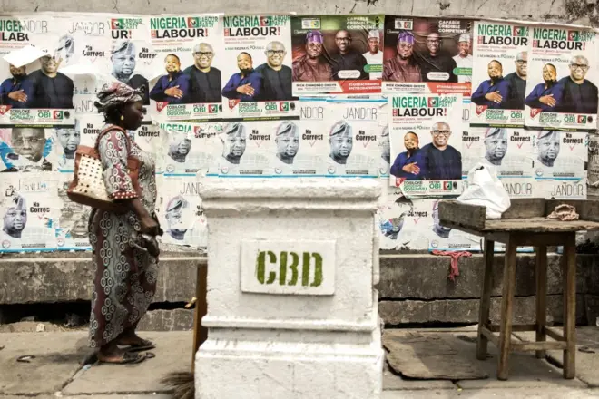 Une femme passe devant un mur avec des affiches des candidats à l'élection