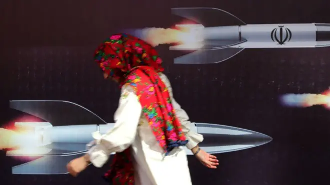 عبورزنی از مقابل یک دیوارنگاره با تصویر موشک در تهران