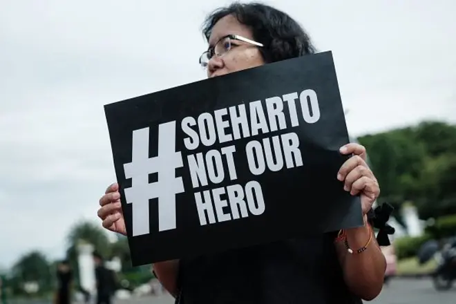 Seorang anggota kelompok gerakan masyarakat sipil memegang poster selama rapat umum yang menentang rencana pemerintah Indonesia untuk memberikan gelar "Pahlawan Nasional" kepada mantan presiden Suharto di dekat istana presiden di Jakarta pada 6 November 2025.
