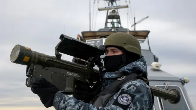 Un soldat ukrainien tient un gros canon antiaérien à bord d'un bateau en mer Noire.