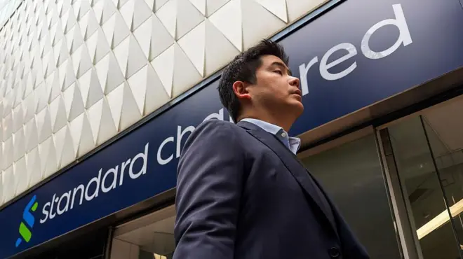 A pedestrian walks past a Standard Chartered bank branch on 17 March, 2026 in Hong Kong.