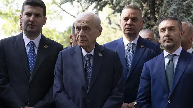 Devlet Bahçeli MHP'nin kurucu genel başkanı Alparslan Türkeş'in kabrini ziyaret ediyor, yanında takım elbiseli kişiler var