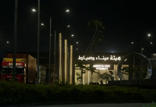 قرب ميناء دمياط المطل على البحر الأبيض المتوسط ​​في محافظة دمياط في مصر. في الصورة الملتقطة ليلاً يظهر مبنى مضاء باللون الأصفر وكتب عليه بالعربية والإنجليزية "هيئة ميناء دمياط"