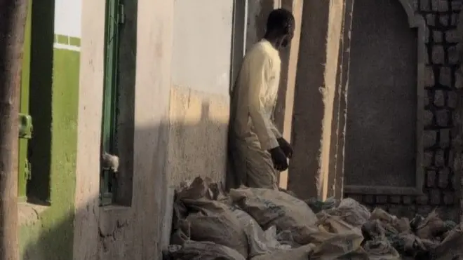 A man standing in front of a home with several bags in front of the house