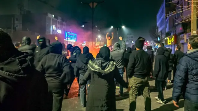 شامگاه ۹ ژانویه معترضان در محله تهرانپارس تهران شبانه در اطراف آتشی در جریان اعتراضات سراسری ایستادهاند و شعار میدهند.