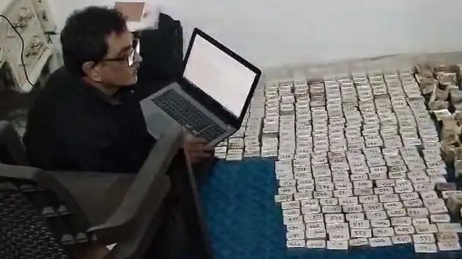 लोकायुक्त के अधिकारी बरामद किए गए कैश की जांच करते हुए. 