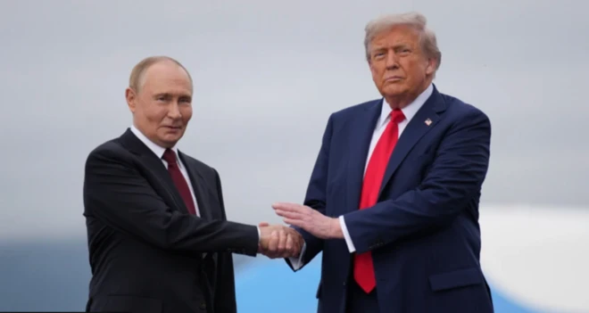 Vladimir Putin ve Donald Trump el sıkışıyor. Trump sol elini de Putin'in elinin üzerine koyuyor