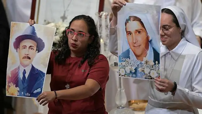 Una mujer sostiene un retrato de José Gregorio Hernández y una monja de la madre Carmen Rendiles, los primeros santos venezolanos